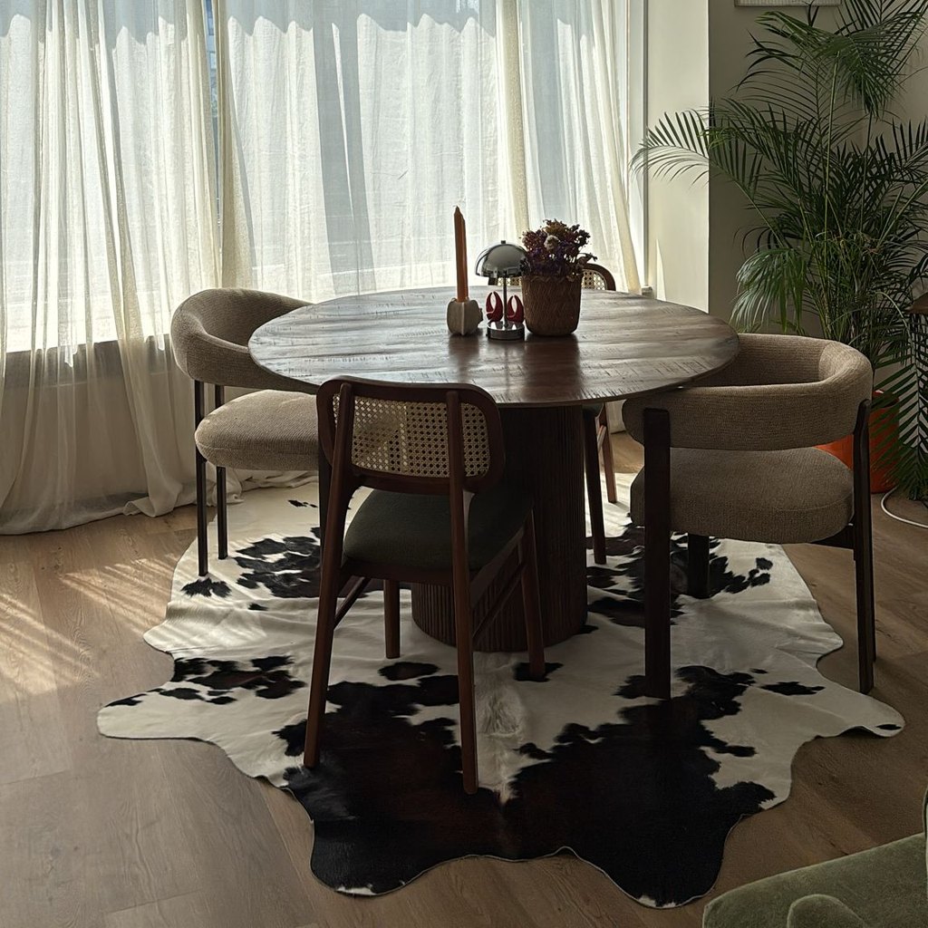 Zwart-wit koeienhuid vloerkleed van een klant, onder een ronde eettafel
